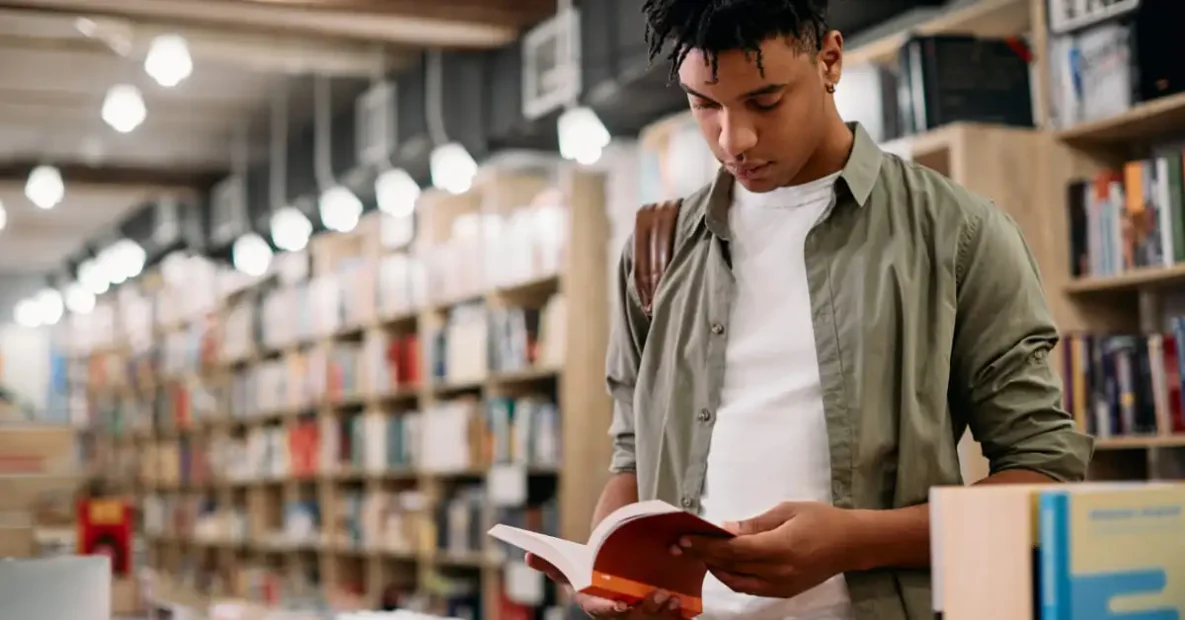 Jovem estudante negro conferindo livro em livraria