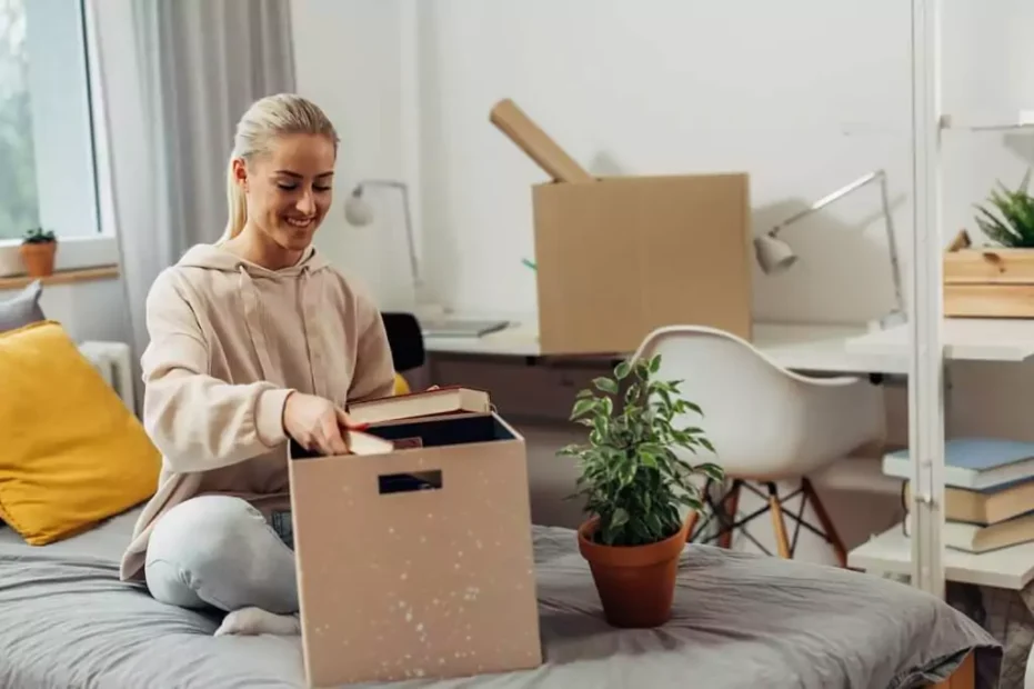 moça arrumando caixa com pertences em quarto