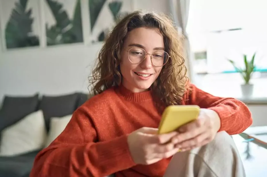 moça sorridente mexendo em celular