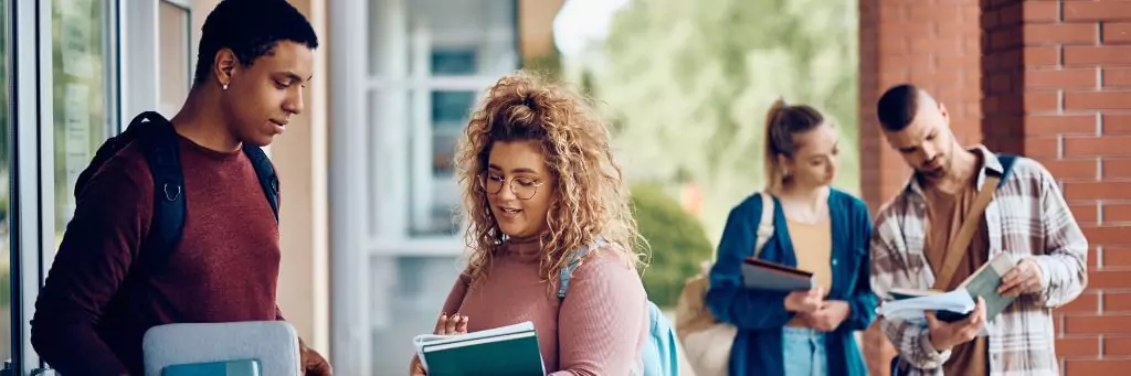 estudantes em faculdade conversando e olhando livros