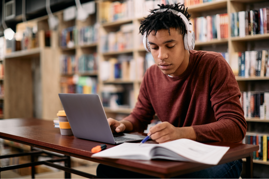 Homem estudando no computador em uma biblioteca. Cursinho para concurso. 