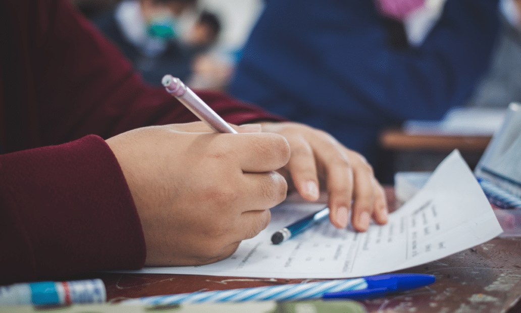 Imagem aproximada das mãos de um estudante fazendo uma prova. Segunda fase Unicamp.