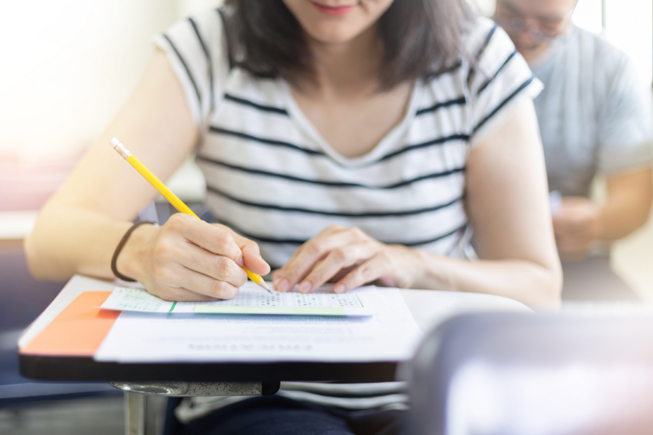 Mulher fazendo prova em sala de aula. Enem dos concursos.