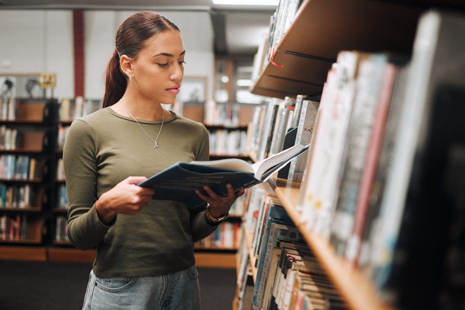 Jovem lendo em biblioteca. Linguagens códigos e suas tecnologias.