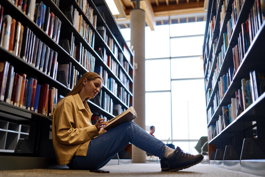 Jovem lendo em biblioteca. Linguagens códigos e suas tecnologias.